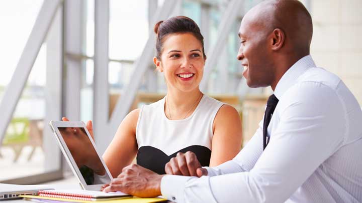 Mulher e Homem sorrindo sentados usando um laptop