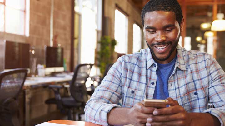 Homme souriant en utilisant son téléphone