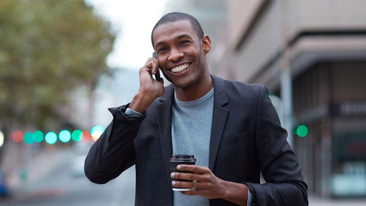 Man die lacht aan de telefoon terwijl hij op straat loopt