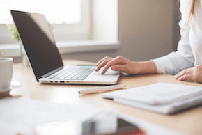 A woman sitting at her desk working on a laptop