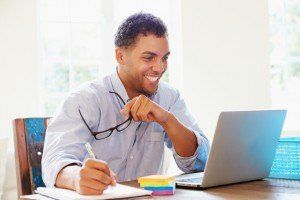 Businessman Working In Office At Home Looking At Laptop Smiling